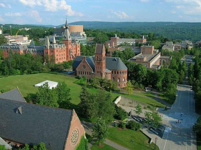 An aerial view of Cornell University's campus, featuring red-bricked buildings and greenery.