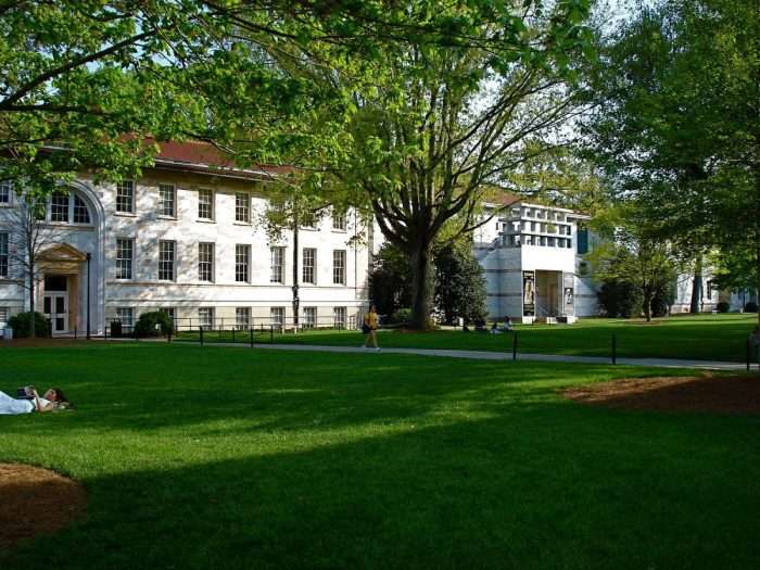 A student reads on a lawn in front of a white building at Emory University.