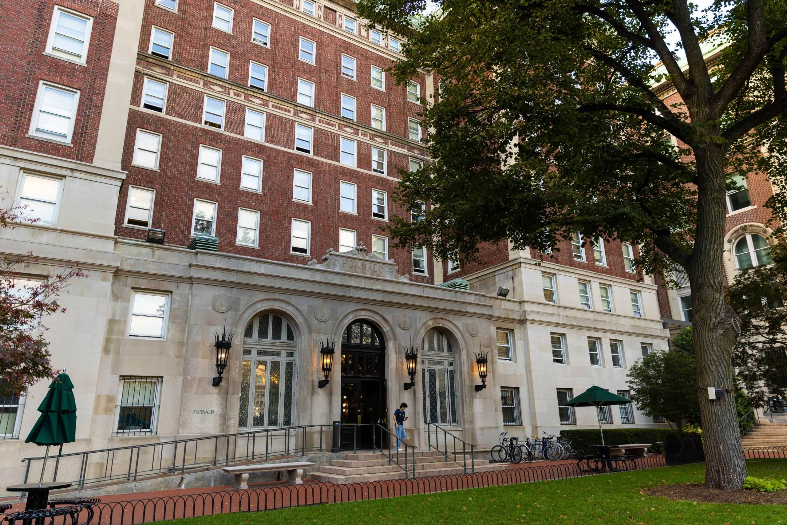 A person exits a red brick building at Columbia University.