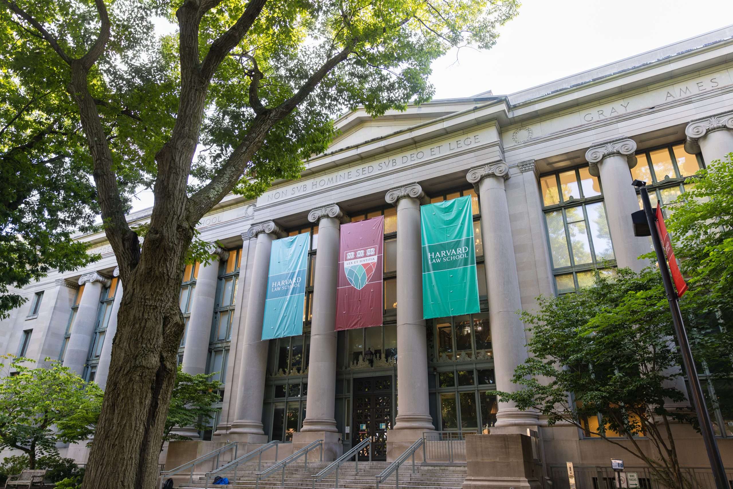 The exterior of Harvard Law School is featured, with flags flying from the roof.