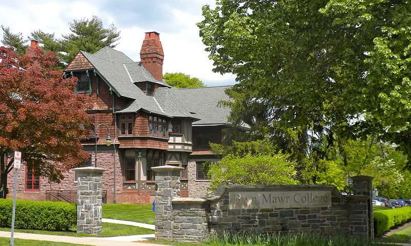 A sign reading Bryn Mawr College is featured in front of a campus building.