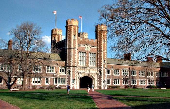 A building at Washington University in St. Louis with two flags flying overhead.