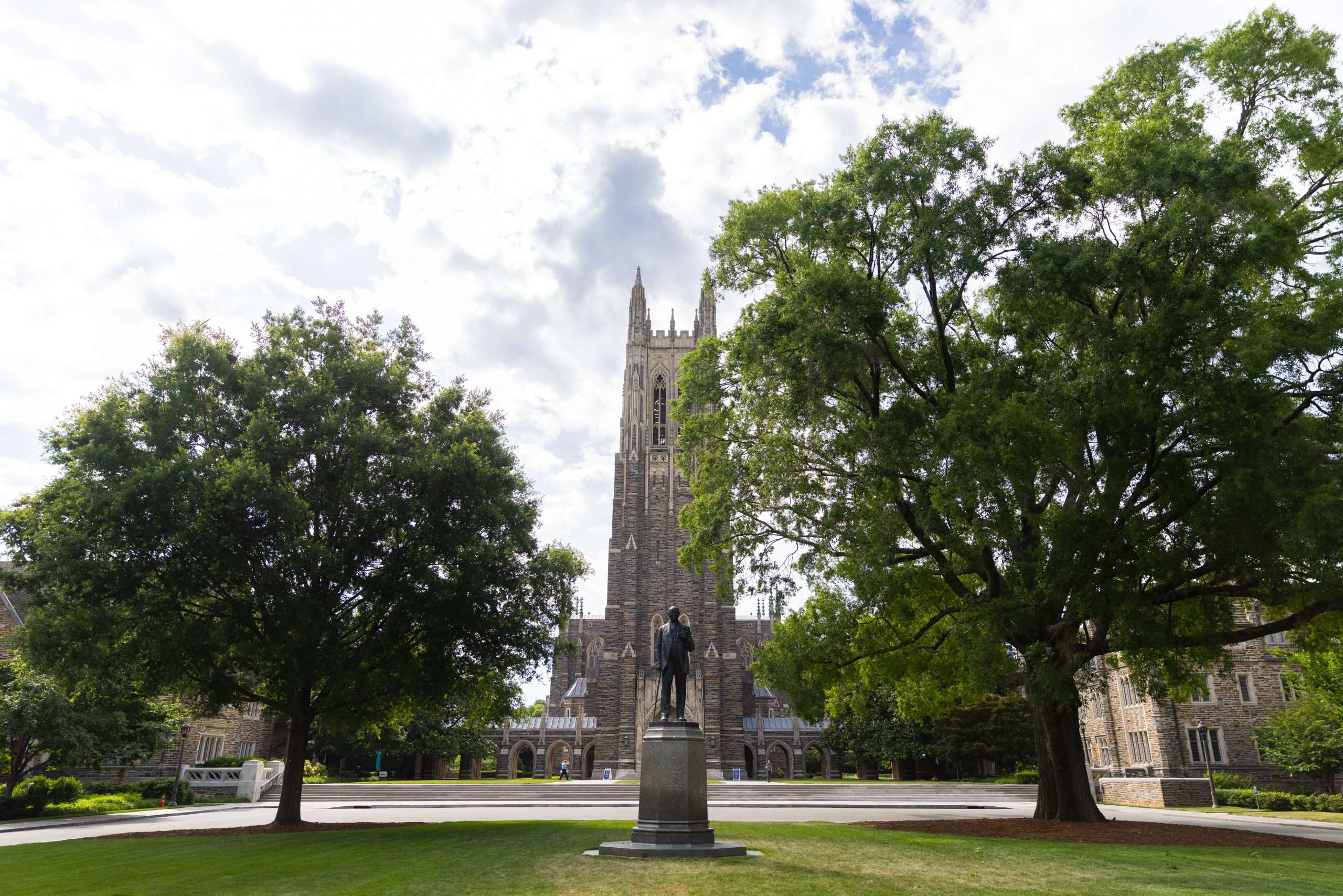 The statue of James B. Duke is in the foreground with Duke University's gothic architecture in the background.