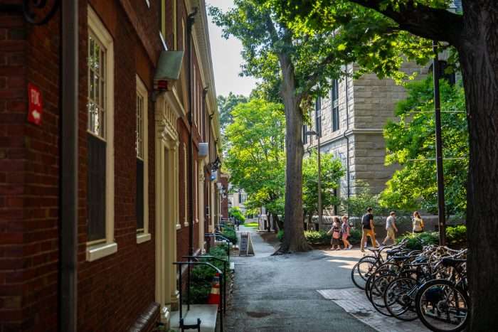 Bicycles are featured on a rack next to a brick building at Harvard University.
