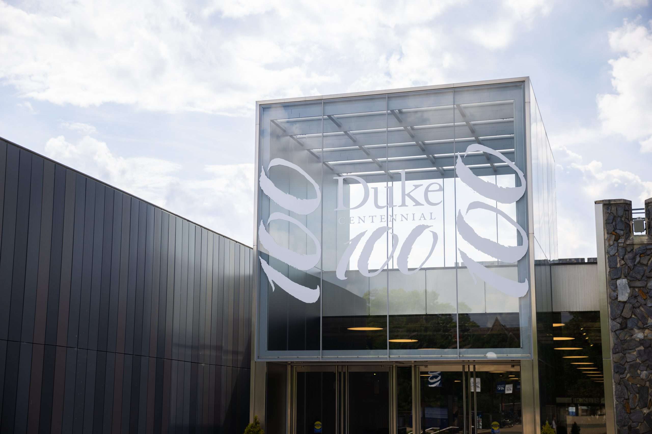 A glass atrium is featured at Duke with writing denoting Duke's centennial celebration.