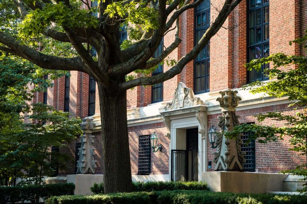 A brick building is featured at Harvard University with the Harvard crest over the front door.