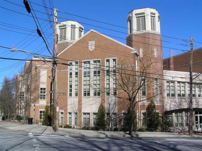 Horace Mann School is featured behind a nearby NYC street under a blue sky.