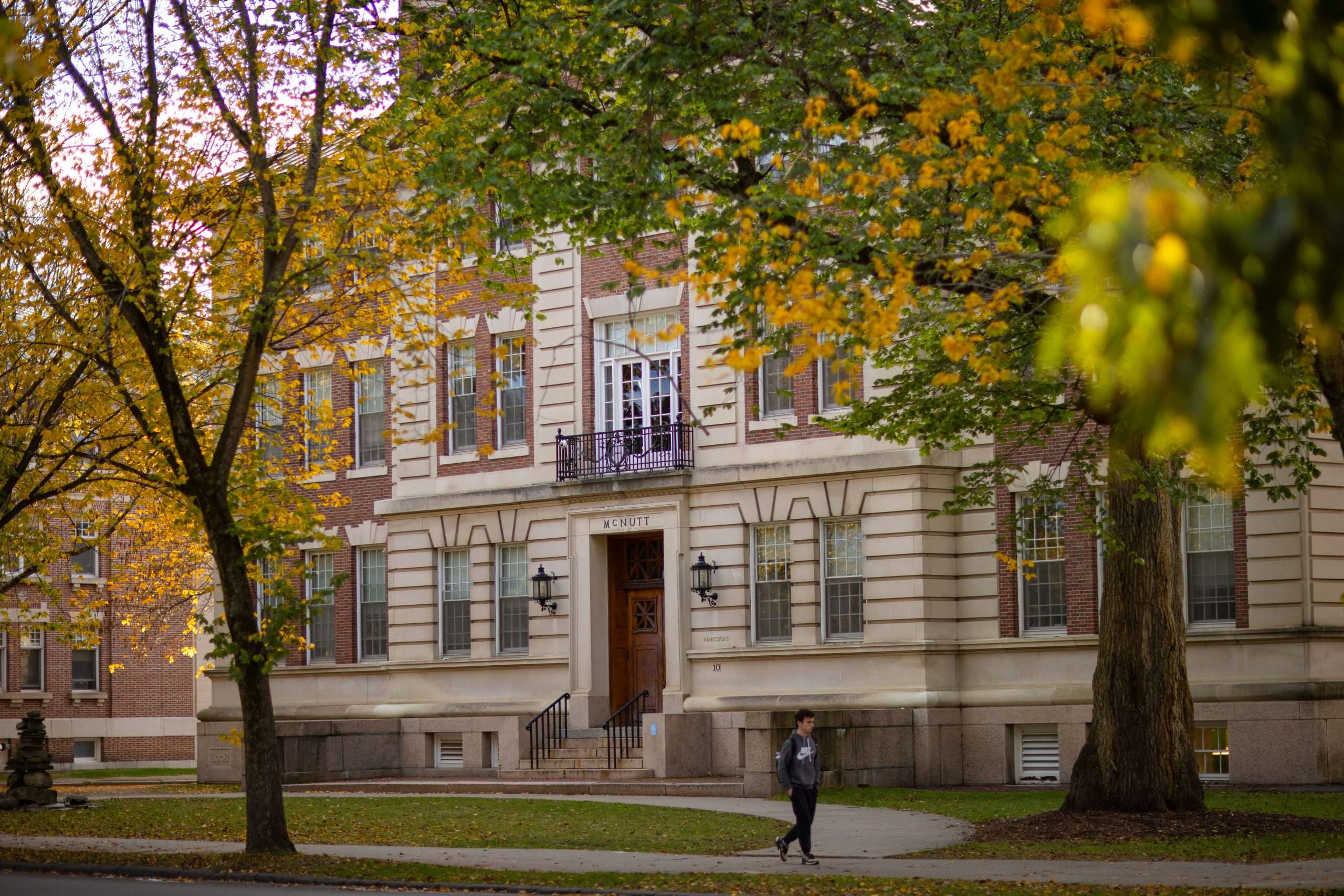 A student walks on the sidewalk in front of McNutt Hall at Dartmouth College.