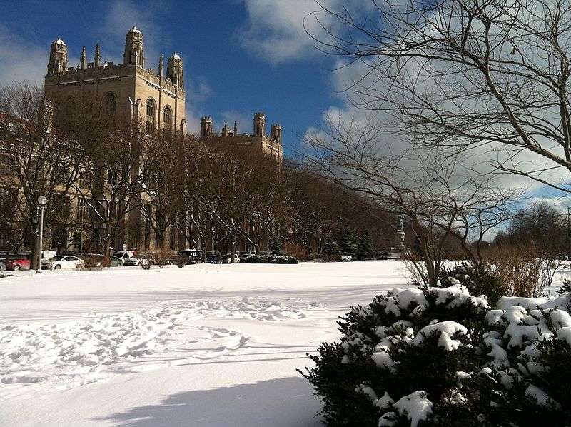 The gothic architecture of Yale's campus is featured beyond a snowy lawn.