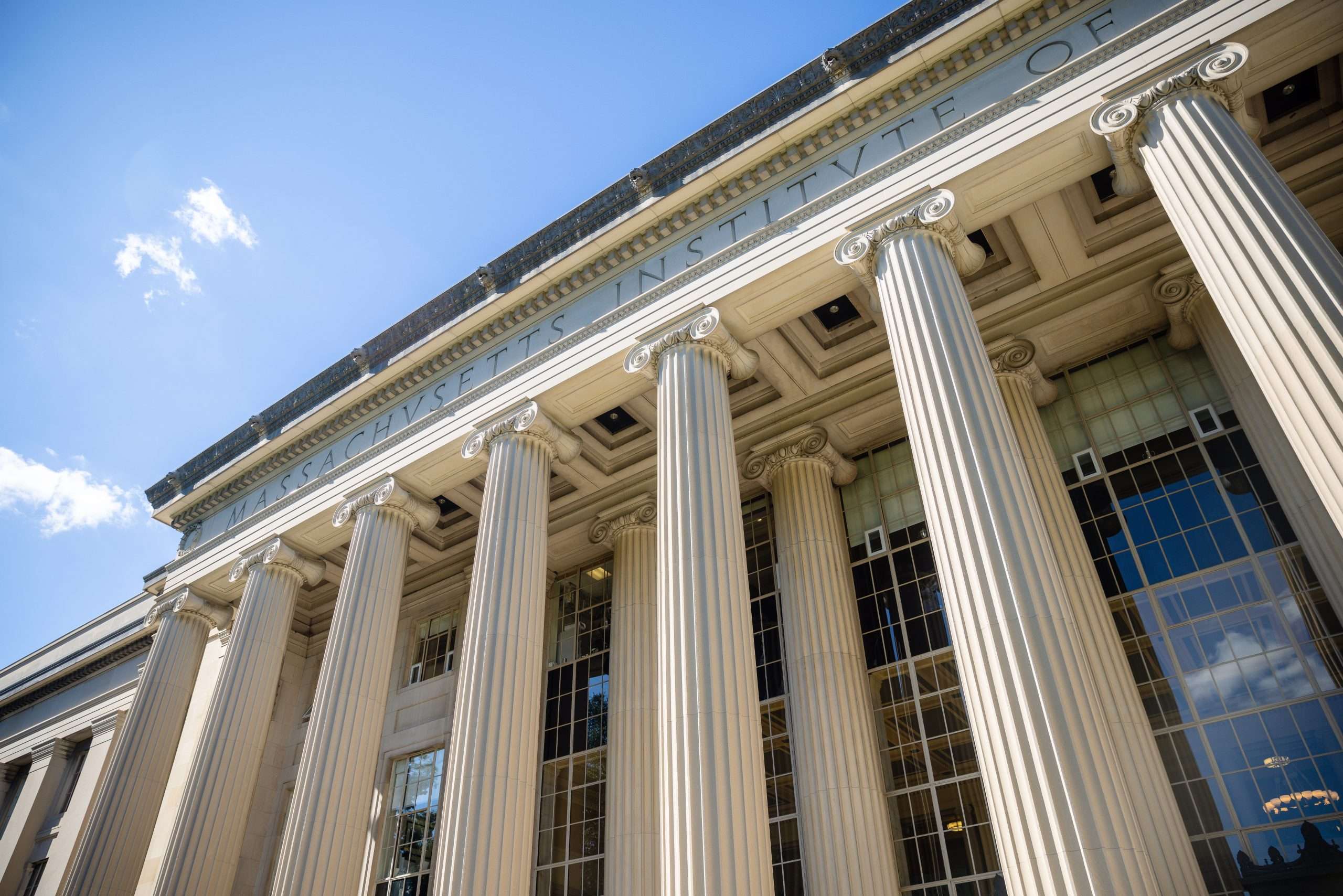 A view of a white columned building at the Massachusetts Institute of Technology from below.