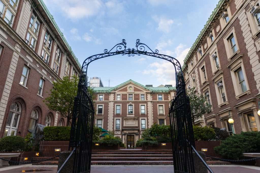 Columbia University’s red-bricked buildings are featured beyond the black iron gates.