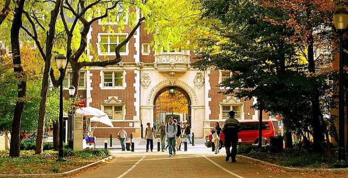 Students walk across the University of Pennsylvania's campus under an arch.