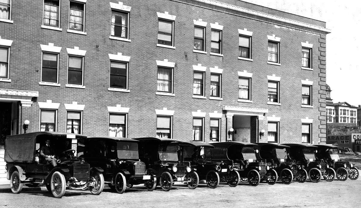 This is a black and photo of cars lined up in front of a building.
