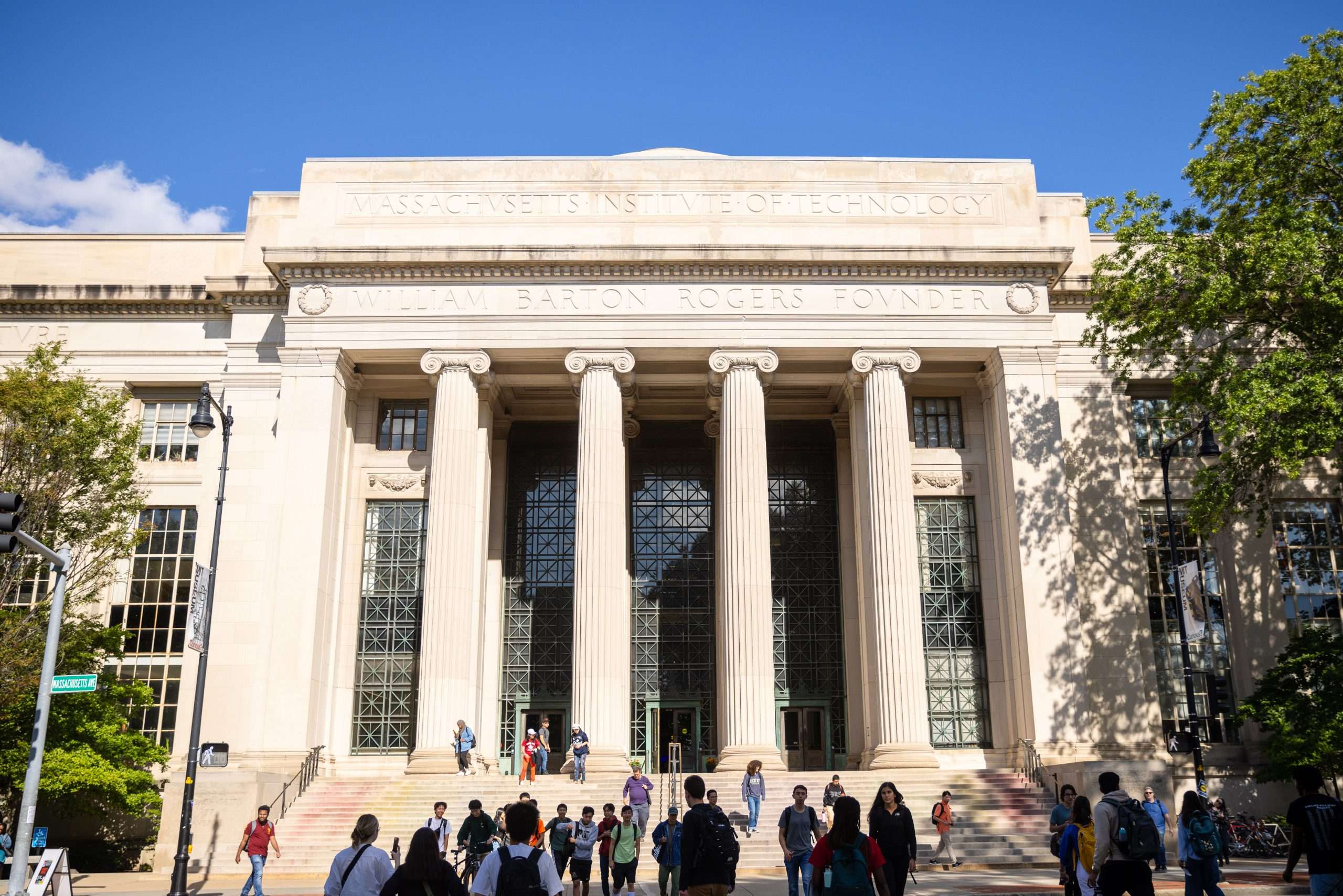 Students gather in front of a columned building with a set of steps out front at the Massachusetts Institute of Technology.