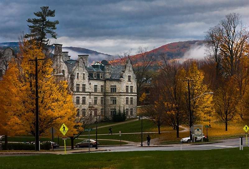 Yellowing trees shed their leaves in front of a campus facility in the hills.
