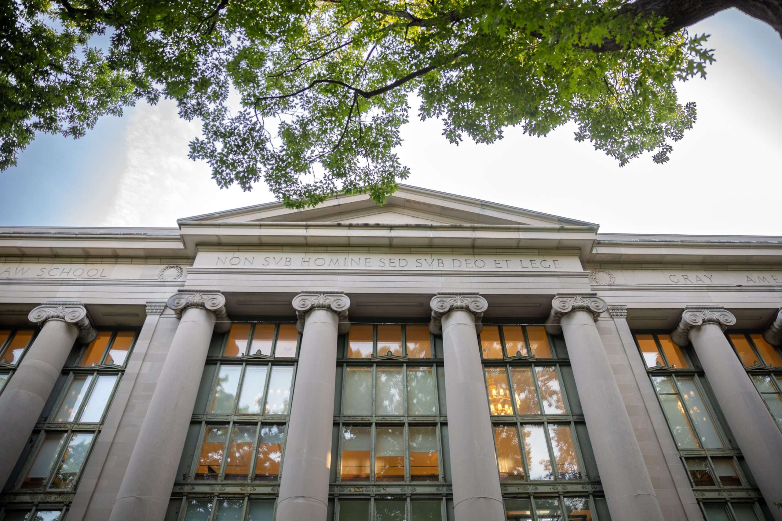 A look up at a glass, columned building at Harvard University.