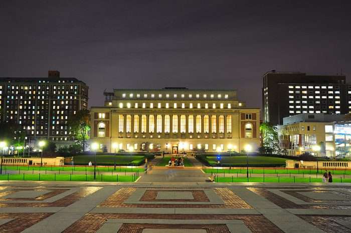 Columbia University's library is lit up under the night sky.