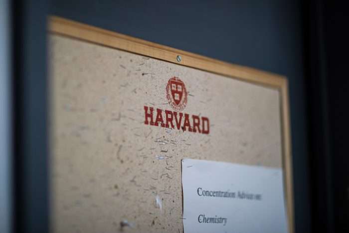 A bulletin board is featured with the Harvard logo emblazoned on it and a paper pinned to it listing Harvard concentrations.